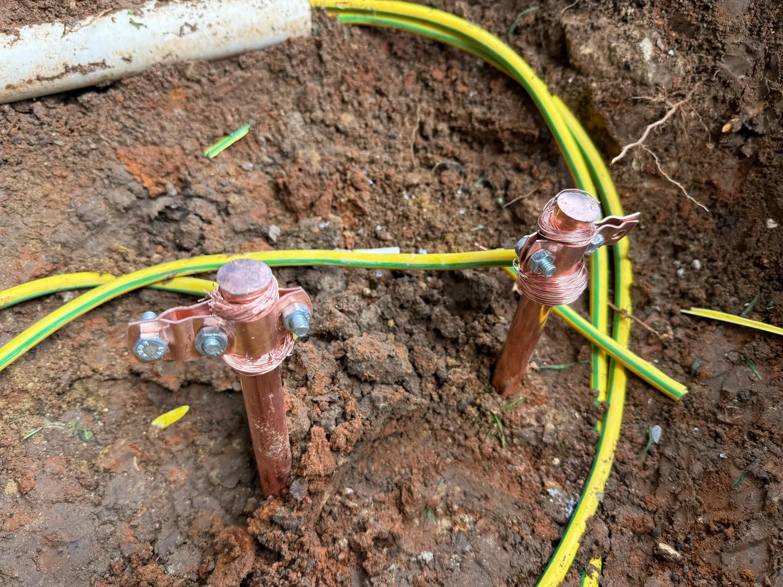 Toprağa çakılan bakır topraklama çubukları ve sarı-yeşil iletkenin klemens bağlantısı
