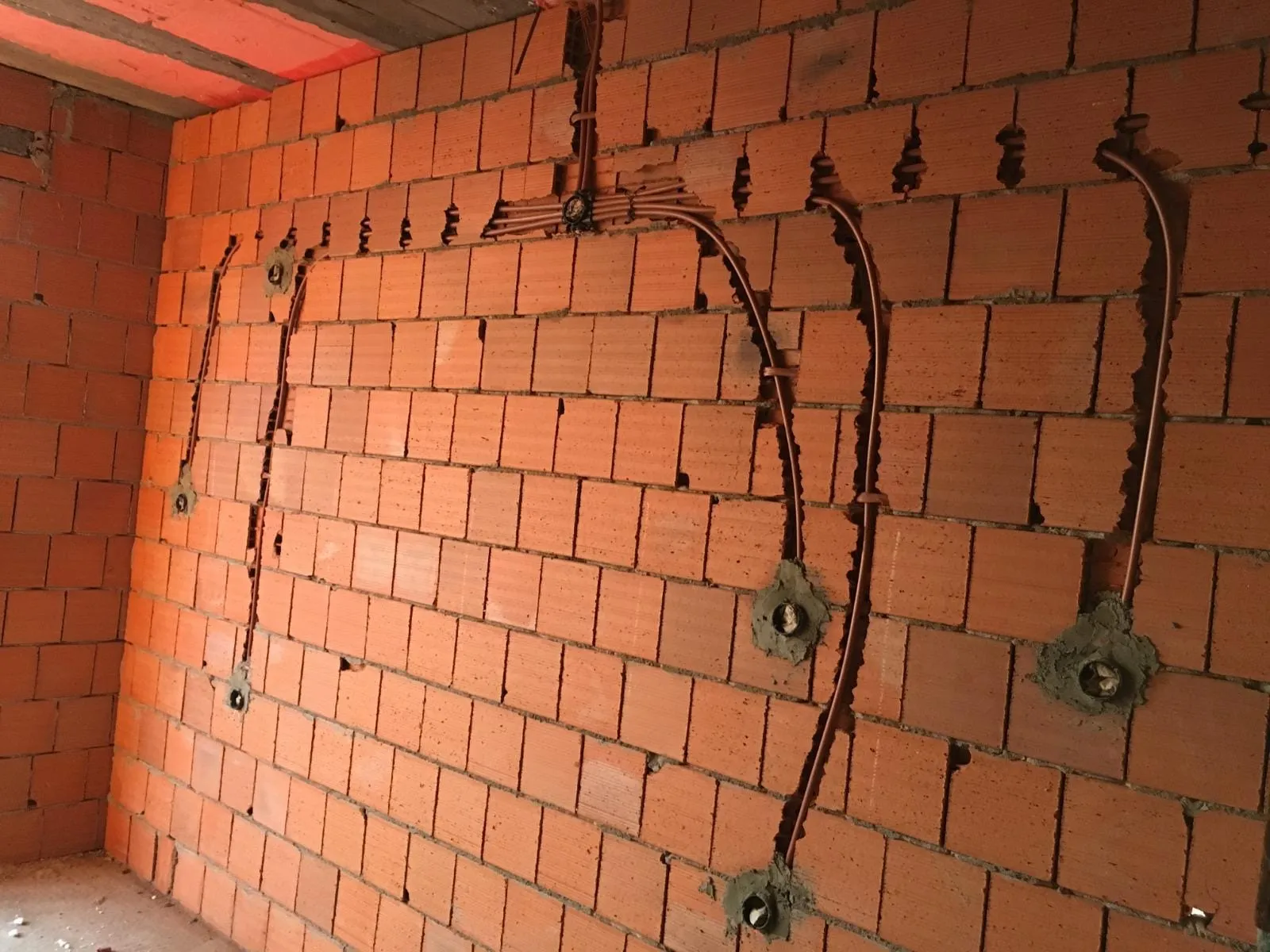 Duvar boyunca açılan priz ve anahtar kutuları ile boru hatları