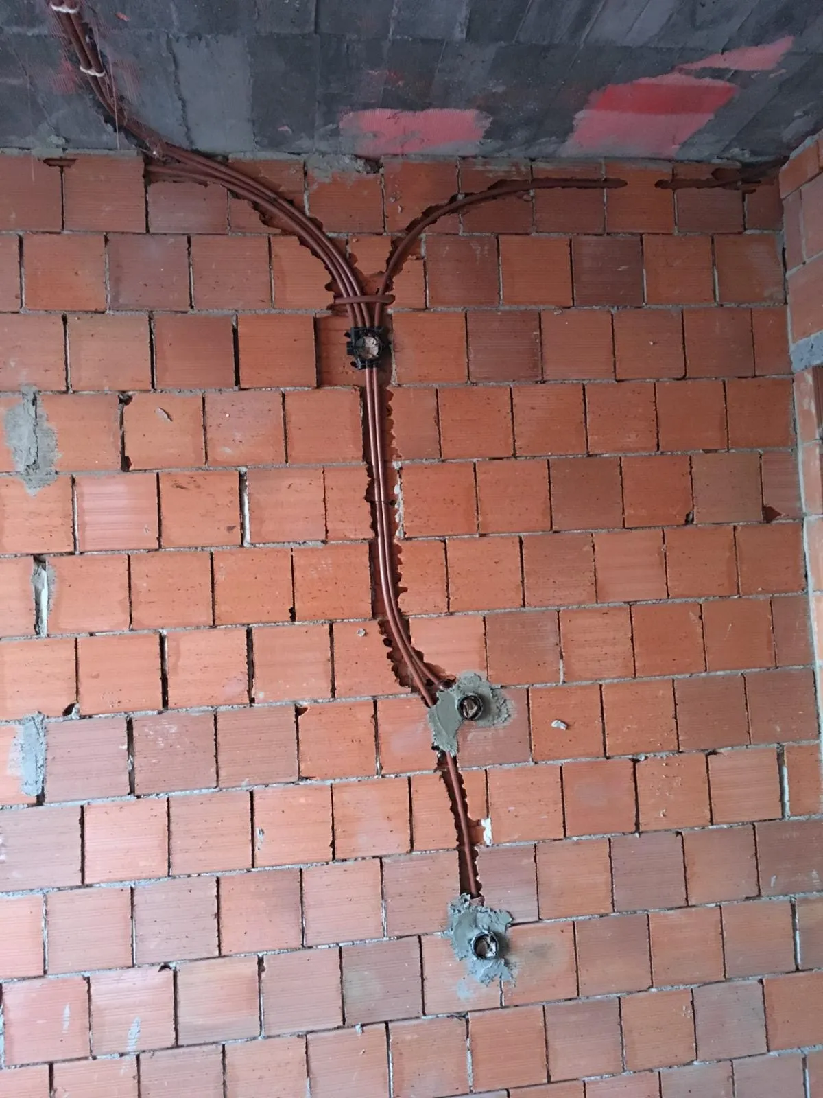 Tuğla duvarda tavandan inen spiral boru hatları ve buat yerleri