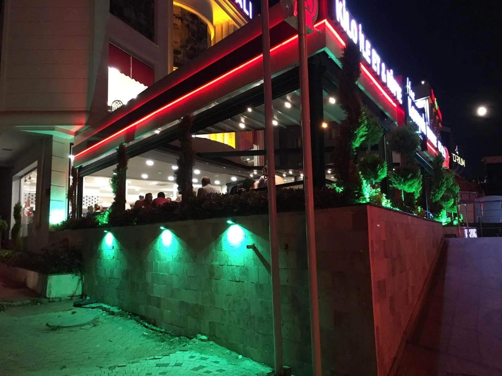 Restoranın yan cephesinde yeşil zemin aydınlatması ve kırmızı LED çizgi