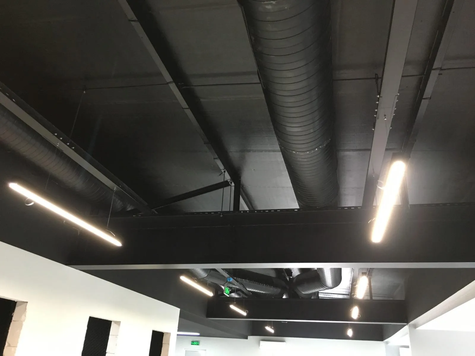 Açık tavanda havalandırma kanalları arasında asılı lineer LED armatürler