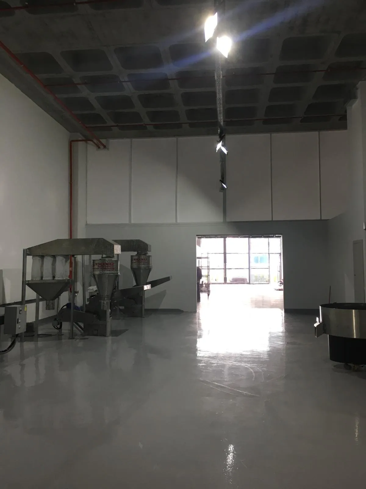 Yüksek tavanlı atölyede ray spotlar ve makine yerleşimi