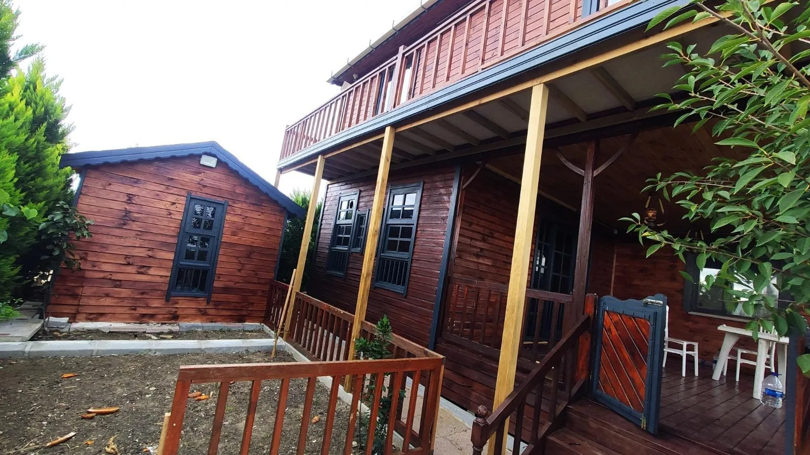 Verandalı ahşap ev ve bahçedeki küçük ahşap yapı