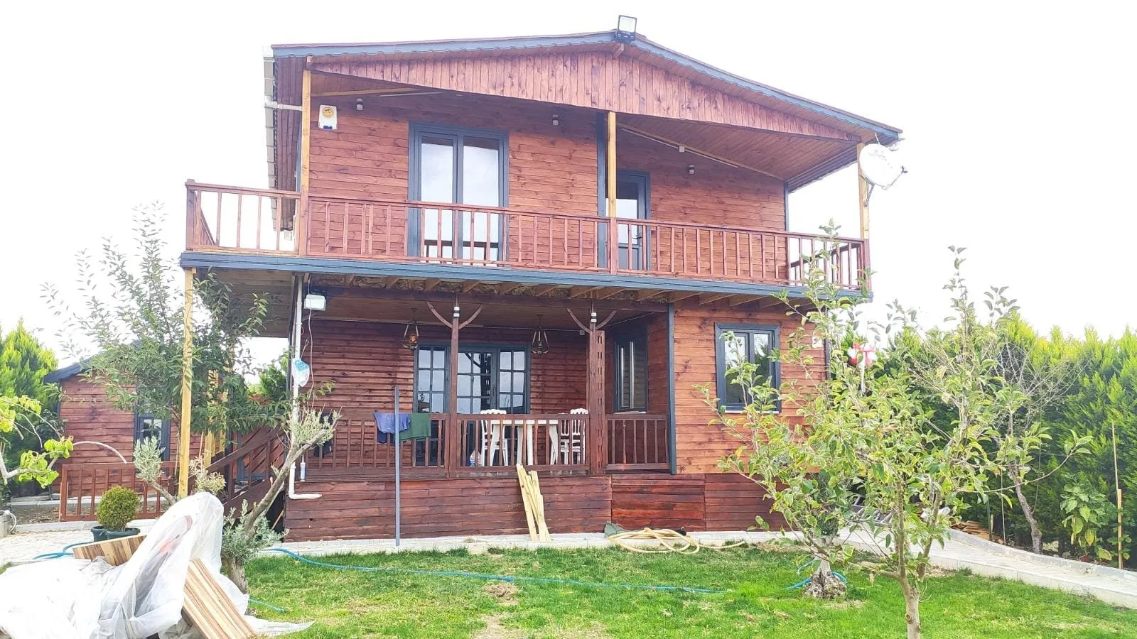 Ahşap evin tamamlanmış hâli: balkon, veranda ve bahçe
